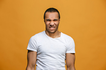 Young man with disgusted expression repulsing something, isolated on the orange