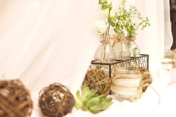 Simple but luxury rich table setting for a wedding celebration in nice cozy restaurant. Wineglasses, plates and bouquet of summer seasonal flowers on a table. Sunlight from a window. Copy space