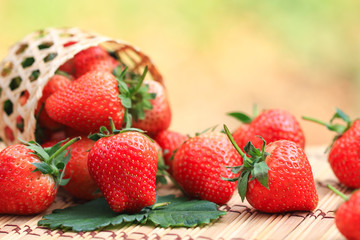 Fresh strawberries in a baske on the table blurred natural green background with copy space