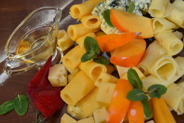 Assorted sliced cheese with mildew, blue, brie, swiss , cheddar, maasdam on the wooden background. fruit and olive oil