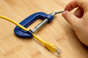 A net neutrality concept image consisting of an internet cable that is being clamped. This image...