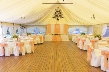 Simple but luxury rich table setting for a wedding celebration in nice cozy restaurant. Wineglasses, plates and bouquet of summer seasonal flowers on a table. Sunlight from a window. Copy space