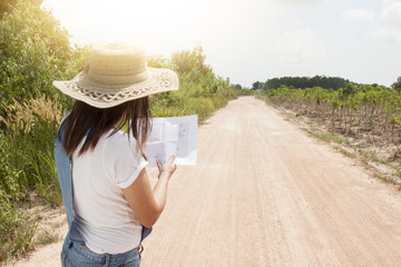 Asia women show hand  purpose of the route on hand have map navigator on soil road.