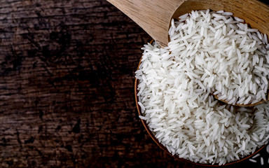 Jasmine rice in wooden bowl with wood ladle on old wood background, Dark tone, Copy space