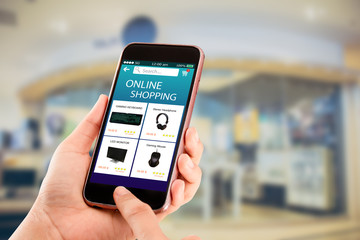Online shopping concept.Hands holding mobile phone on blurred shop as backround