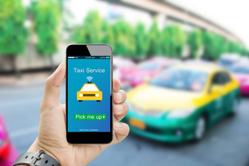 Online Taxi service concept.Hands holding mobile phone on blurred taxi car as background