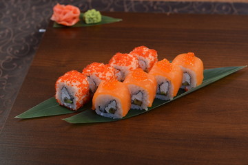 Sushi roll with salmon and shrimp tempura on the leaf. wodden background