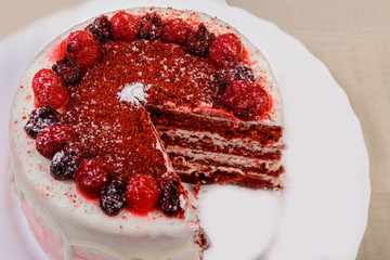 round cake with berries and cream from it cut a piece photographed close-up