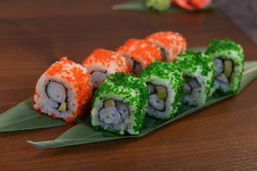 Sushi roll with salmon and shrimp tempura on the leaf. wodden background