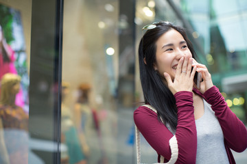 Asia woman sitting and talking with smart phone in the street in a sunny summer day