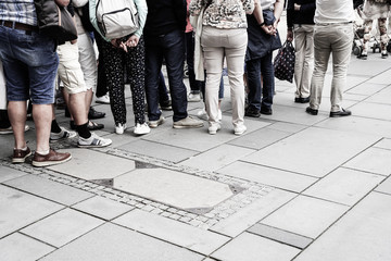 People waiting in line to enter building from waist down