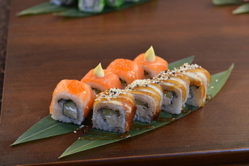 Sushi roll with salmon and shrimp tempura on the leaf. wodden background