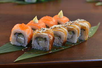 Sushi roll with salmon and shrimp tempura on the leaf. wodden background