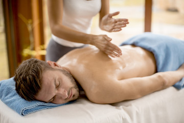 Fototapeta na wymiar Young man having relax massage in the spa