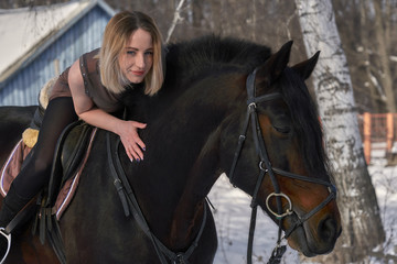 A girl with long blonde hair communicates with her favorite horse. The girl loves animals. Sunny...