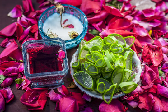 Close up of a herbal face pack consisting of Aloe Vera gel,honey,milk cream,lemon and rose with rose water and rose petals on wooden surface in dark Gothic colors.This face pack removes the dull skin.