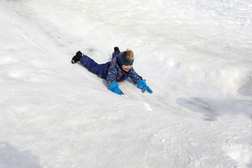 Fototapeta na wymiar Kid sliding down snow hill