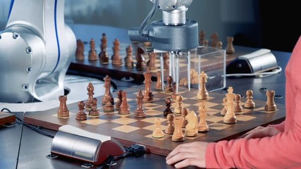 Girl's hands and a robotized arm are moving chess pieces in turns