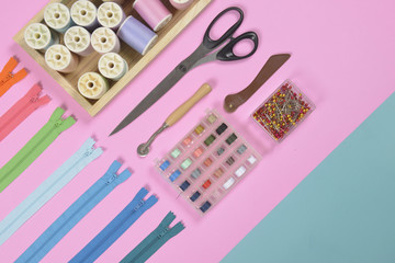 Flat lay of sewing material contains the scissors, measuring tape, zipper, pin and colorful thread...