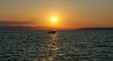 Fototapeta premium Boat at sunset, against sunlight
