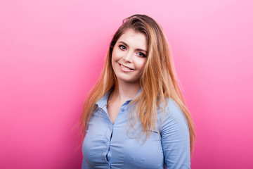 Fototapeta premium Portrait of beautiful blonde woman smiling on pink background