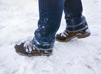 Boots and jeans in the snow. Female legs in jeans and winter boots. View from above. Winter.