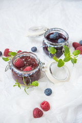 breakfast with blueberry and raspberry jam on a white paper background, decoration with mint leaves