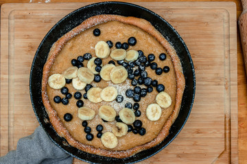 Dutch Baby pancake with blueberries, banana and powdered sugar baked in oven