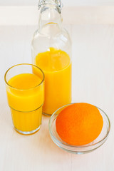 Orange juice in a glass bottle and glass on a white background