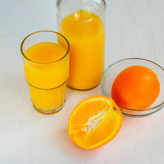 Orange juice in a glass bottle and glass on a white background