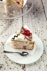 biscuit cake with cream and cherries on wooden background