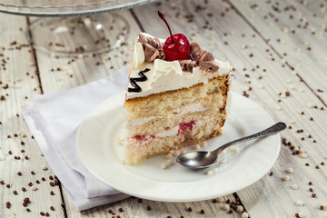 biscuit cake with cream and cherries on wooden background