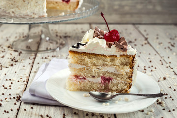biscuit cake with cream and cherries on wooden background