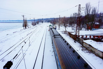 Green train in the winter in snow on rails with ice, a look with top from the foot bridge.  