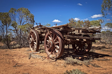 Fototapeta na wymiar Australia – Outback savanna with an old vintage derelict horse-drawn carriage at the bush under blue sky