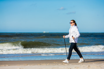 Fototapeta na wymiar Nordic walking - woman training on beach 