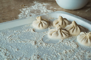 White floured board are blanks of dough products. Wooden table. Close up.