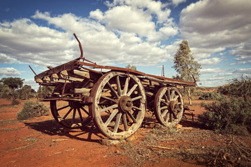 Fototapeta na wymiar Australia – Outback savanna with an old vintage derelict horse-drawn carriage at the bush under cloudy sky
