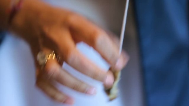 Female hands neatly stringing pieces of Greek nuts on rope, traditional cuisine