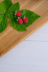 Home juicy raspberries poured in a bowl on a wooden table
