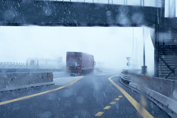 Truck on highway during a snowfall, driving in bad weather with poor visibility.ity.