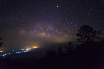 Fototapeta premium The Milky Way Galaxy and silhouette of trees in the mountains. Night scene landscape at Doi Dam view point Chiang mai, Thailand.