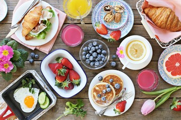 Breakfast food table. Festive brunch set, meal variety with fried egg, pancakes, croissants,...