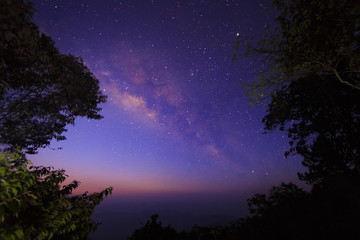 The Milky Way Galaxy and silhouette of trees in the mountains. Night scene landscape at Doi Dam view point Chiang mai, Thailand.