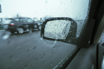 Winter driving, rear car mirror during a snowfall