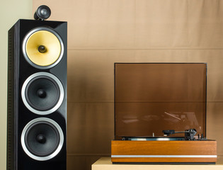 Vintage turntable playing a vinyl record and modern black speakers © Steven