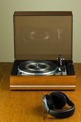 Vintage turntable playing a vinyl record and modern black headphone © Steven