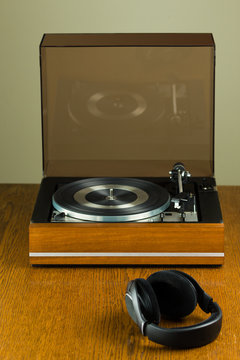 Vintage turntable playing a vinyl record and modern black headphone