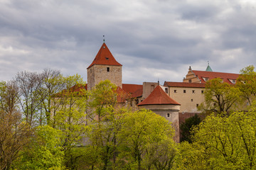 Fototapeta na wymiar Red towers and wall of famous Hradcany castle. Prague, Czech Republic. Gloomy spring weather
