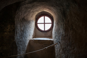 The old round window on the ancient wall of the fortress tower, Europe.